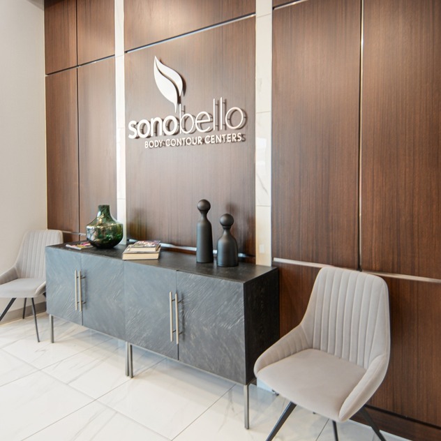 Reception area with a modern design, featuring chairs, a decorative console table, and a logo on the wooden wall.