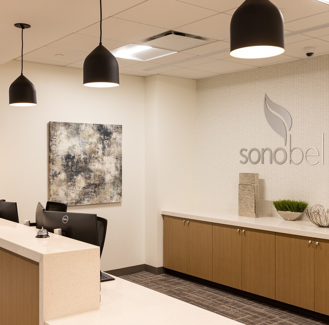 modern office reception with desks chairs overhead lights and wall art