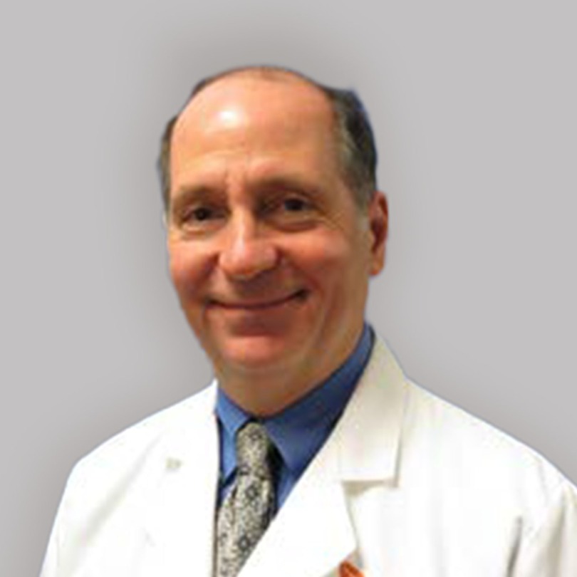 Smiling man in a white lab coat with a tie, against a gray background.