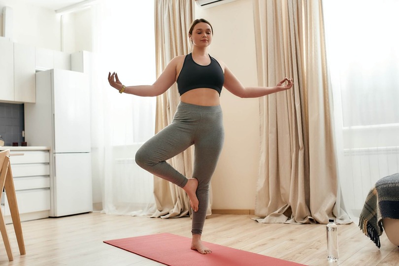 woman in athleticwear holding yoga pose and relaxing at home