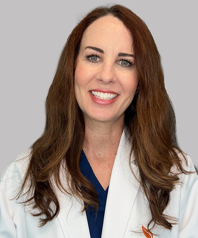 Smiling woman wearing a white coat against a gray background.