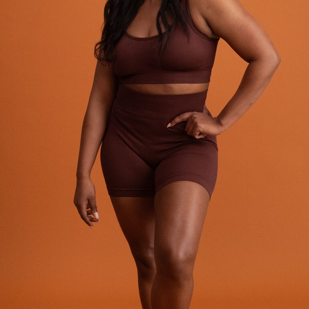 Sono Bello liposuction patient posing in front of orange background