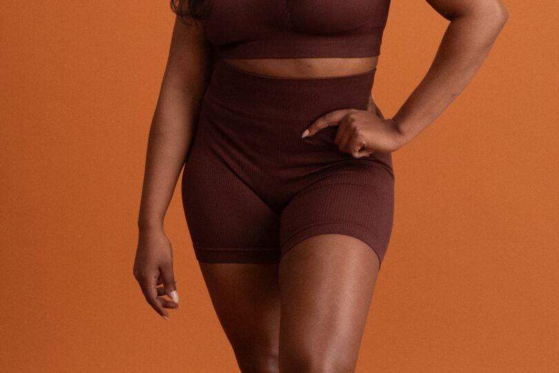 Sono Bello liposuction patient posing in front of orange background