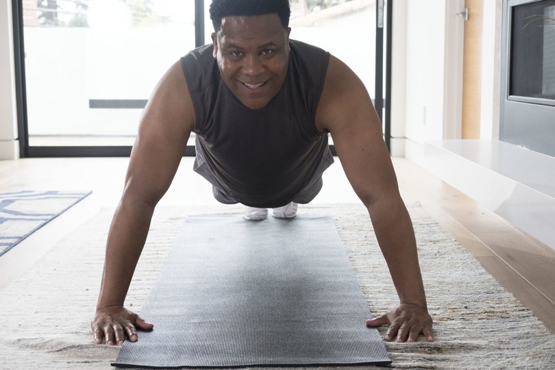 Person doing a push-up on a yoga mat in a bright room.