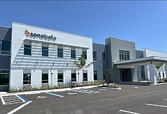 modern building with sonobello sign, large windows, blue sky, accessible parking spaces in front