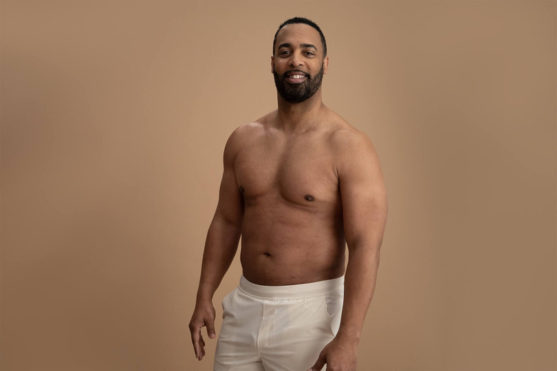 Male ambassador posing with sculpted abs and chest after liposuction