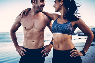 Fit man and woman with flat abs and sculpted chests enjoying active beach day