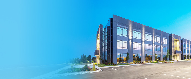 Modern office building with large windows and a clear blue sky in the background.