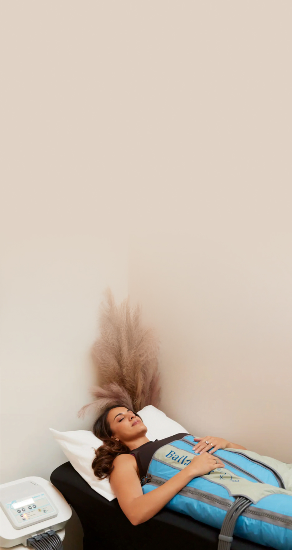 Person lying on a bed with long hair spread out, against a minimalist beige background.