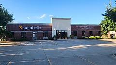 Exterior view of a brick building with Sono Bello and Quad Cities Periodontics signage on a sunny day.