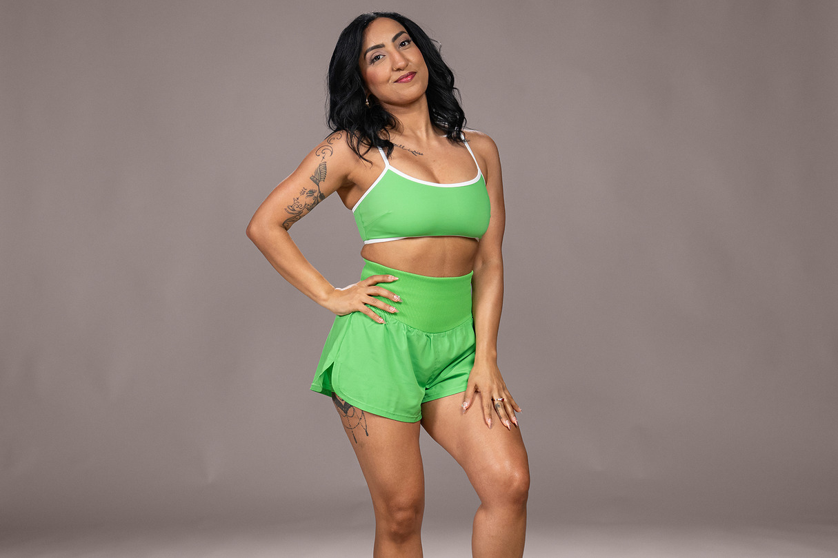 Person posing in green athletic outfit against a neutral background.