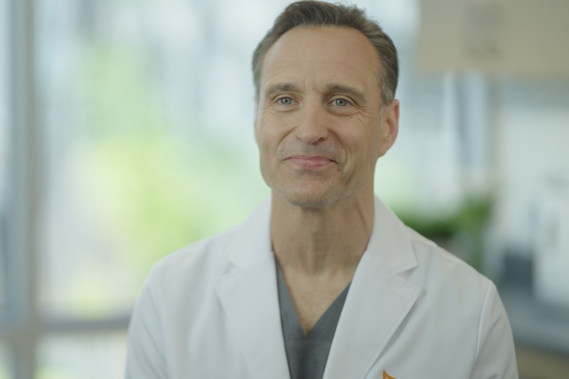 Smiling man in a white coat with blurred background of a bright room