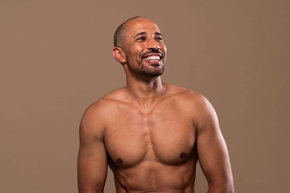 Man smiling while standing against a brown background