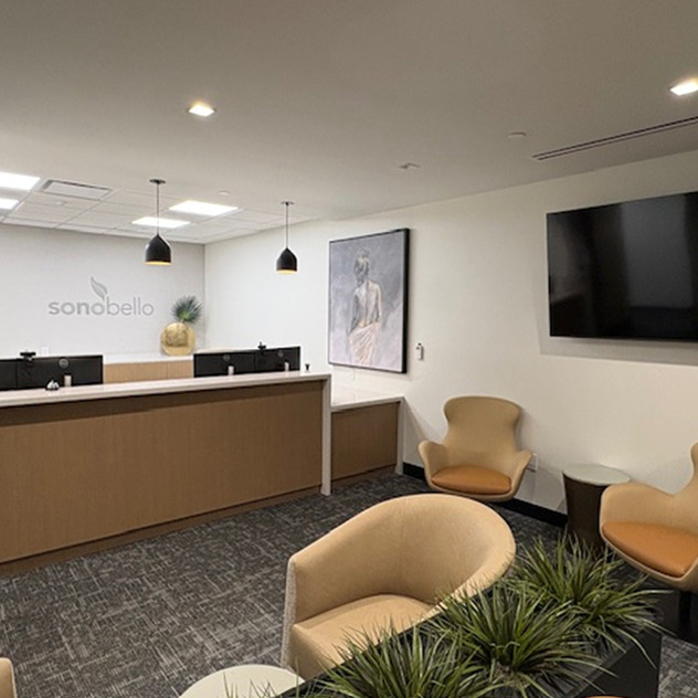 modern office reception area with a seating arrangement, wall art, pendant lighting, and a TV screen