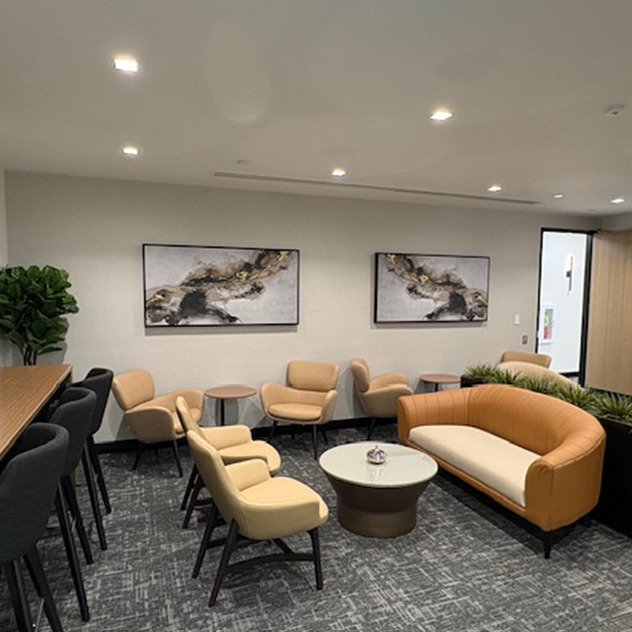 Modern office waiting area with comfortable seating, abstract wall art, and soft lighting.