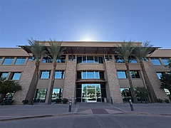 Sono Bello office building exterior with stone facade, large glass windows, and palm trees in a sunny setting, located in Goodyear, Arizona.