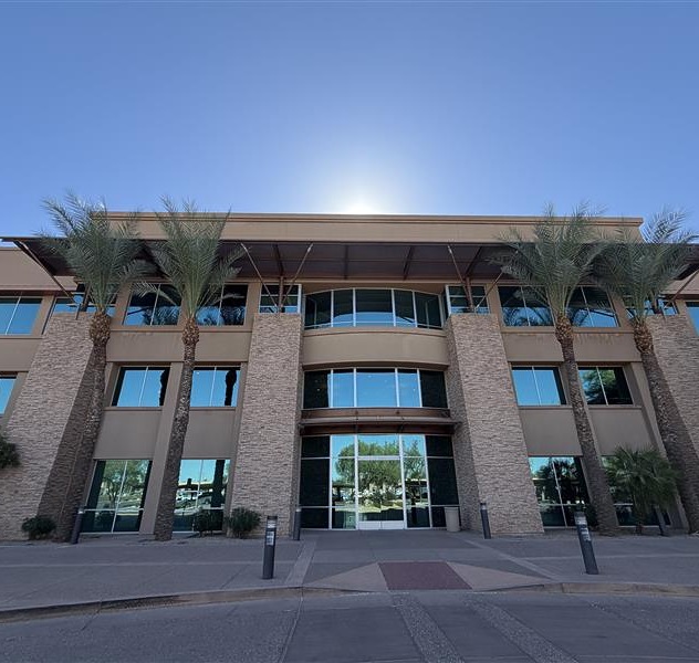 Sono Bello office building exterior with stone facade, large glass windows, and palm trees in a sunny setting, located in Goodyear, Arizona.
