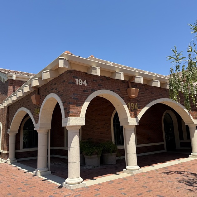 Sono Bello Chico liposuction and body contouring center with arches and columns under a clear blue sky. House number 194 visible on the corner.